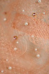 Featuring a delicate net adorned with sparkling crystals and lustrous pearls.