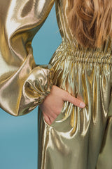 Charming golden silk jumpsuit with a deep V-neck and strings for closure at neckline.