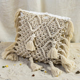 Riviera Square Cushion is made of linen in ivory white and adorned with a hand-knotted macramé in a natural shade.