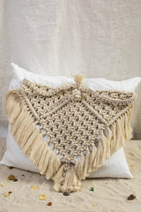 The Riviera Triangle Cushion is made of linen in ivory white and adorned with a hand-knotted macramé in a natural shade.