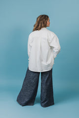 White satin shirt with a scoped hemline that is longer in the back and rounds up on the sides.
