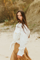 White satin shirt with a scoped hemline that is longer in the back and rounds up on the sides.