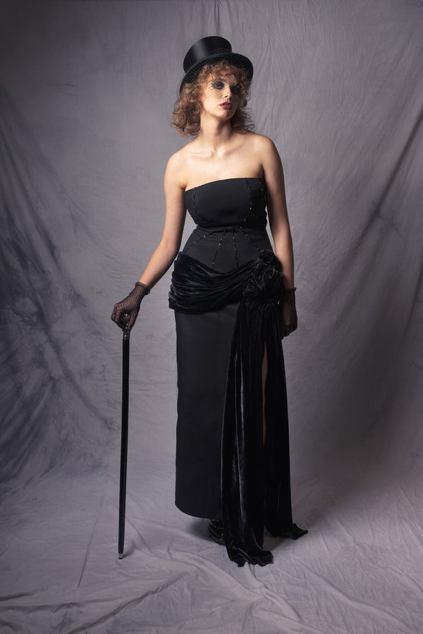 off-shoulder black dress withs a beaded corset top and a silk velvet basque, accentuated by a high slit