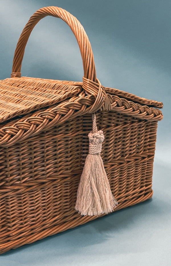 An exquisite wicker picnic basket with a handle and a hinged lid.
