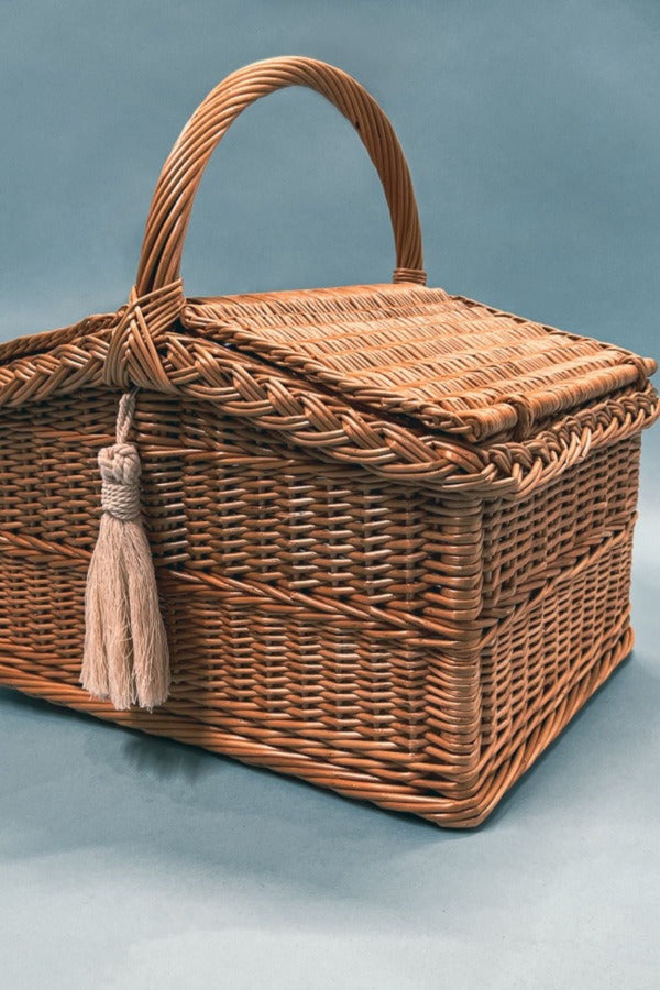 An exquisite wicker picnic basket with a handle and a hinged lid.