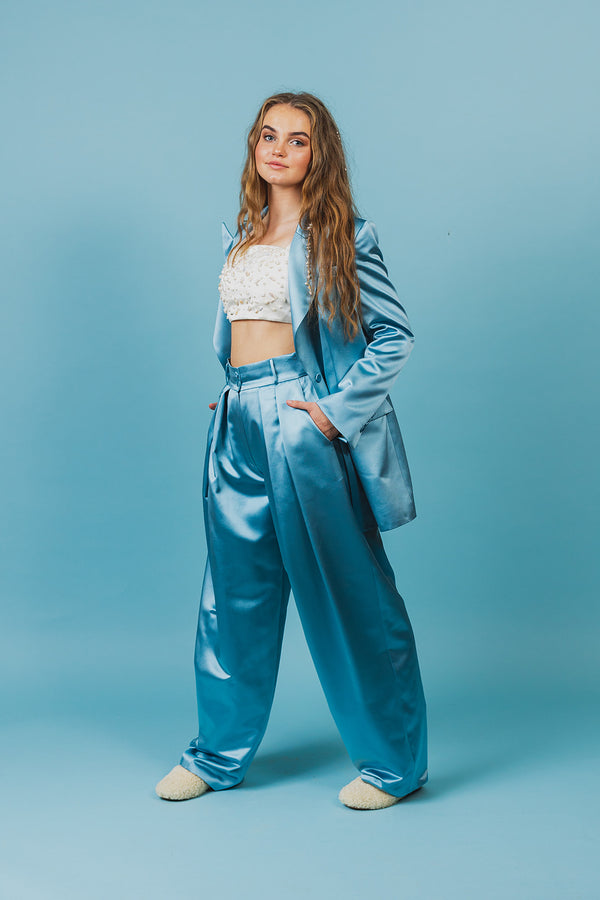 Elegantly tailored summer sky blue glossy silk wide-leg trousers with a high waist and a front button and zipper fastening.